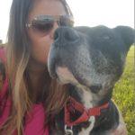 A woman kisses a dog with dark fur.