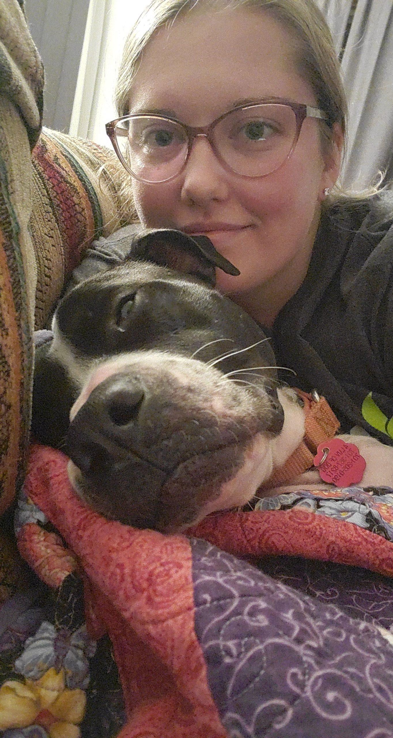 A woman takes a selfie with a black and white dog.