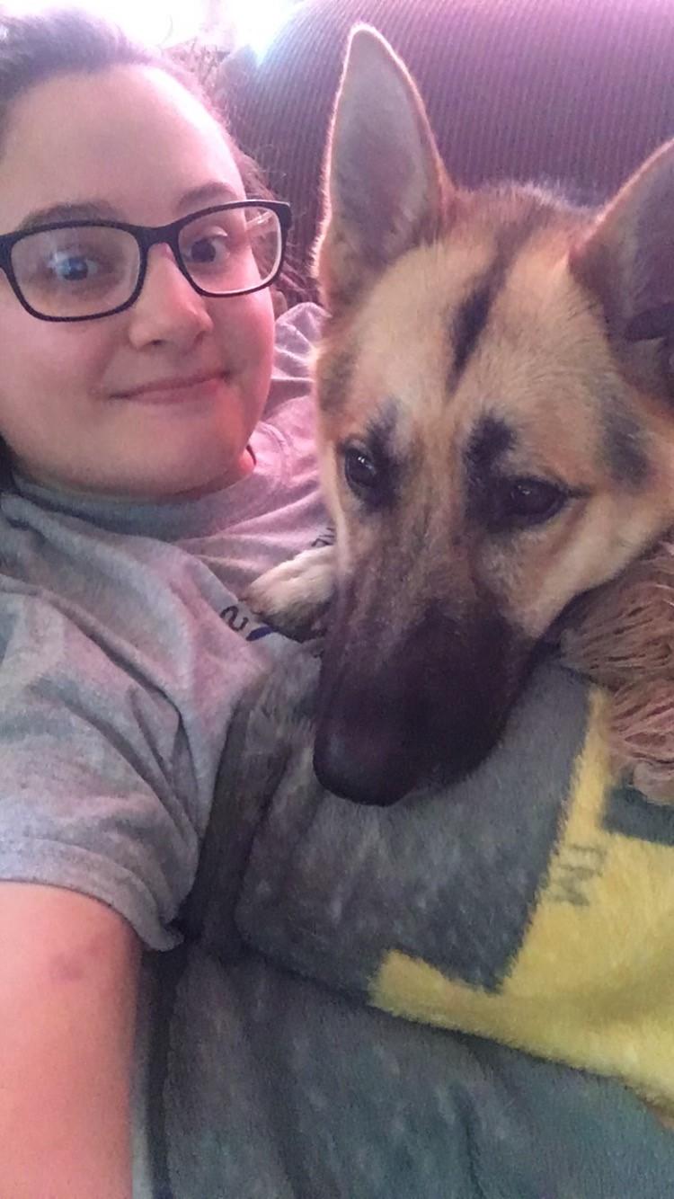 A woman takes a selfie with a German Shepherd. Its ears are pointed straight up.